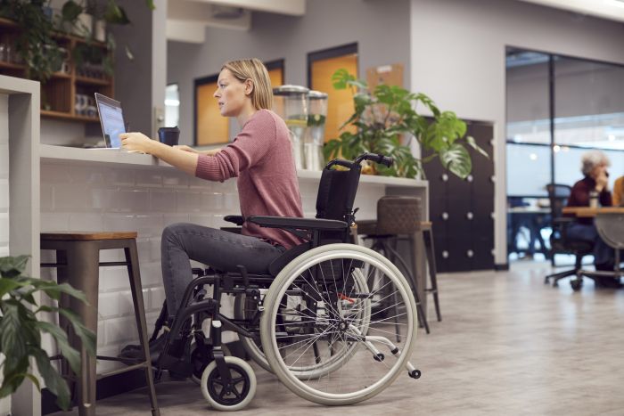 female actor seated in a wheelchair uses a laptop